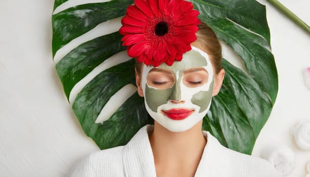 Skin care. Cheerful attractive caucasian female with clay mask on face and cucumber slices in hands against blue background getting beauty treatment. Spa concept with copy space
