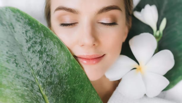 Portrait of beautiful woman with healthy glow perfect smooth skin holds tropical leaf, look into the hole of green paper. Young girl enjoys cream facial mask. Fashion, beauty, skincare concept.