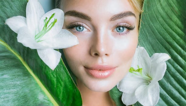 Portrait of beautiful woman with healthy glow perfect smooth skin holds tropical leaf, look into the hole of green paper. Young girl enjoys cream facial mask. Fashion, beauty, skincare concept.