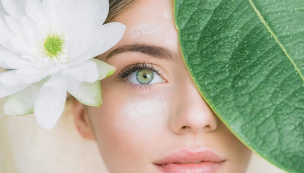Portrait of beautiful woman with healthy glow perfect smooth skin holds tropical leaf, look into the hole of green paper. Young girl enjoys cream facial mask. Fashion, beauty, skincare concept.