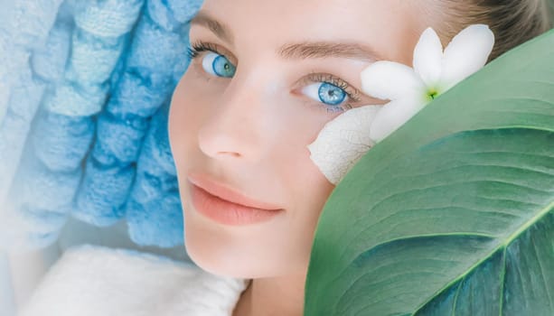 Portrait of beautiful woman with healthy glow perfect smooth skin holds tropical leaf, look into the hole of green paper. Young girl enjoys cream facial mask. Fashion, beauty, skincare concept.