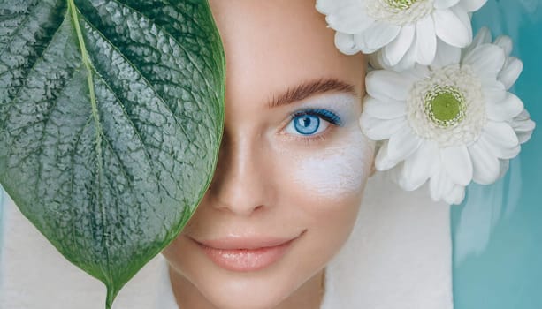 Portrait of beautiful woman with healthy glow perfect smooth skin holds tropical leaf, look into the hole of green paper. Young girl enjoys cream facial mask. Fashion, beauty, skincare concept.