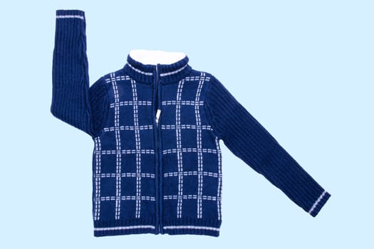 Autumn and winter jacket. A dark blue woolen knitted cardigan or pullover with       a white checkered pattern on light blue background. Kids cozy warm jumper or  sweater fashion.