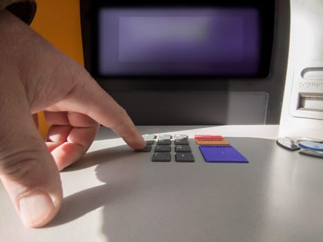 Mature man finger pressing password number on ATM machine. Accesible keypad