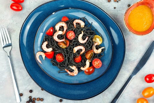 Vegan black bean spaghetti with shrimp and tomatoes.