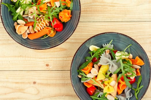 Salad with fresh tomatoes, greens and pasta on a plate.