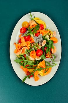 Salad with fresh tomatoes, greens and pasta on a plate.
