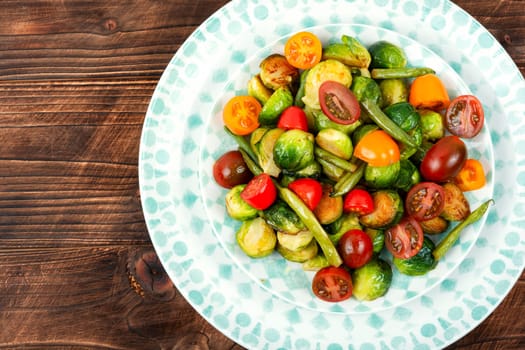 Salad of roasted brussels sprouts, tomatoes and green beans. Healthy vegan food concept. Flat lay with copy space