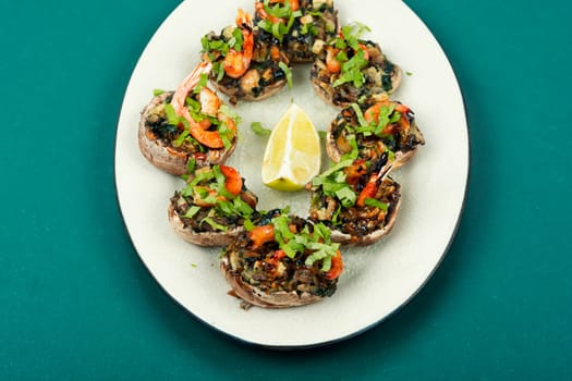 A platter of baked champignon mushroom caps stuffed with shrimp, prawns.
