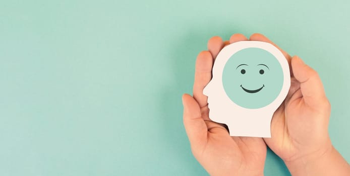 Holding a head with a happy smiling face in the hands, mental health concept, positive thinking, support and evaluation
