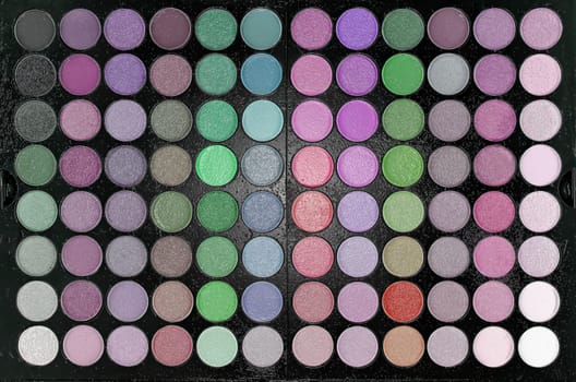 A toy plastic multicolored large professional makeup kit for face and eyes in close-up. Texture or background