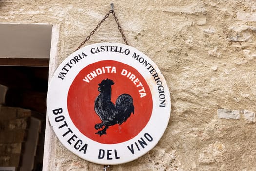 Monteriggioni, Italy - Sept 17, 2022: Black rooster symbol of good wine in Tuscany hanging on the wall of a house in Monteriggioni medieval walled town near Siena. Italy