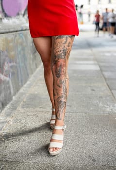 young woman with tattooed legs walking under bridge