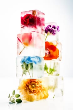 A tower of ice cubes with vibrant flowers encapsulated inside, showcasing a blend of nature and creative design.