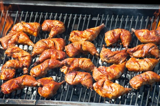 Spicy Marinated Chicken legs grilling on a summer barbecue .