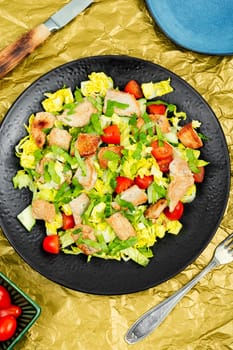 Salad with green lettuce, cucumber, tomatoes and pieces of meat. Top view.