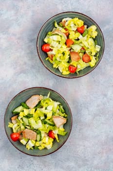 Salad with green lettuce, cucumber, tomatoes and pieces of meat. Top view.
