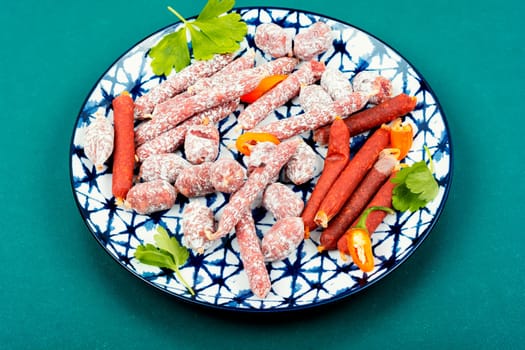 Three varieties of salami sausage on a plate, meat appetizer. Top view.