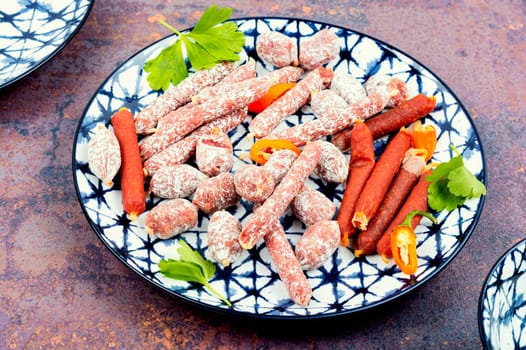 Three varieties of salami sausage on a plate, meat appetizer. Top view.