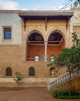 Serene courtyard showcases the timeless beauty of Mamluk architecture with high big arches and stonework with welcoming staircase leading to ornate balcony