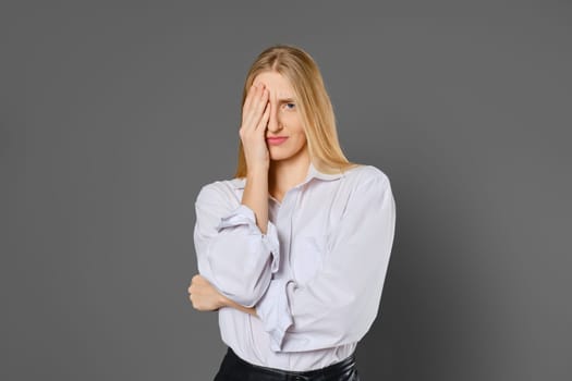 Portrait of a tired and frown young woman covering one eye with her palm