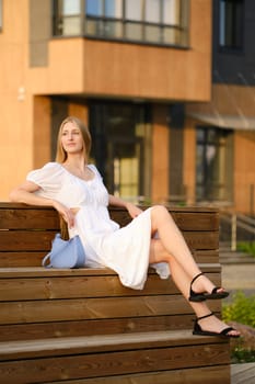 Young blonde woman sitting on bench in residential area