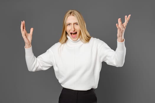 Angry young woman swears and gesticulates emotionally with her hands