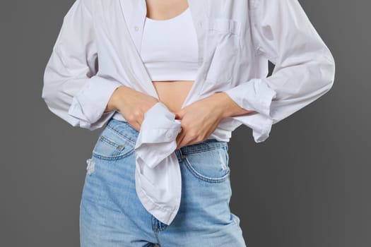 Unrecognizable woman tying a shirt at her waist