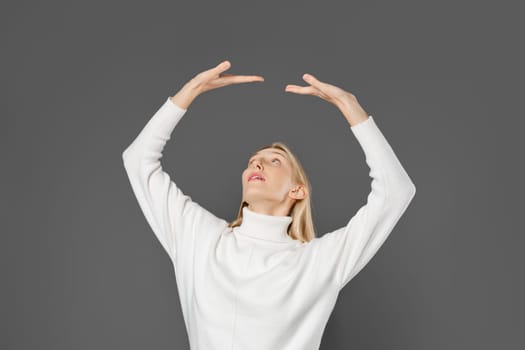 A young woman raised both hands, palms up, as if she were resting on an invisible ceiling