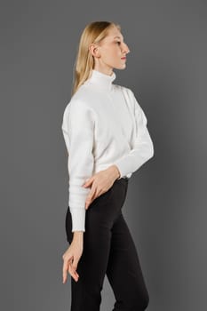 Young woman pulling up sweater sleeve standing in profile