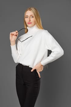 Portrait of a serious young woman holding her glasses in hand