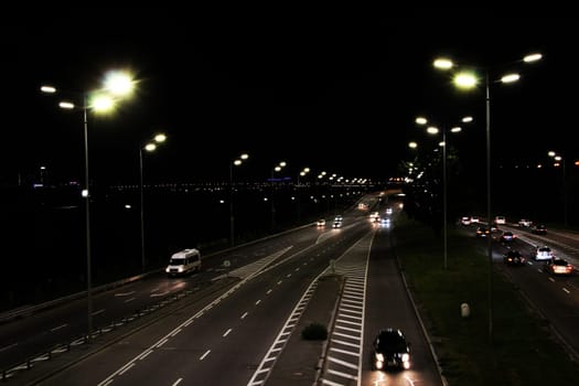 Evening transport. Cars on the night highway. Multi-lane road in Kyiv at night. Illuminated street of evening city. Cars going along night city