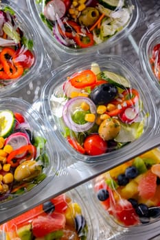 Plastic boxes with pre-packaged vegetable salads, put up for sale in a commercial refrigerator