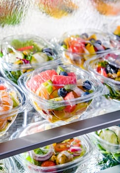 Plastic boxes with pre-packaged fruit salads, put up for sale in a commercial refrigerator