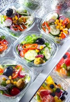 Plastic boxes with pre-packaged fruit and vegetable salads, put up for sale in a commercial refrigerator