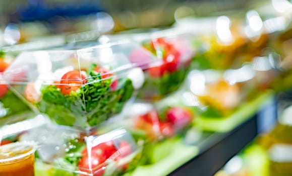 Pre-packaged vegetable salads displayed in a commercial refrigerator