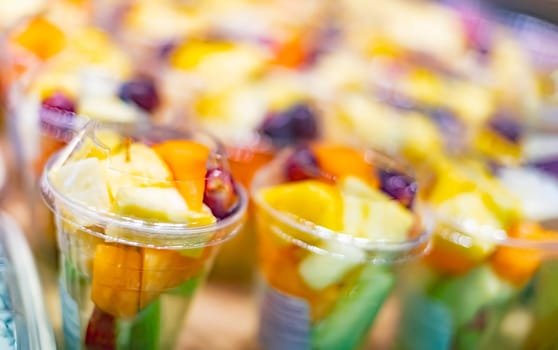 Pre-packaged fruit salads displayed in a commercial refrigerator.