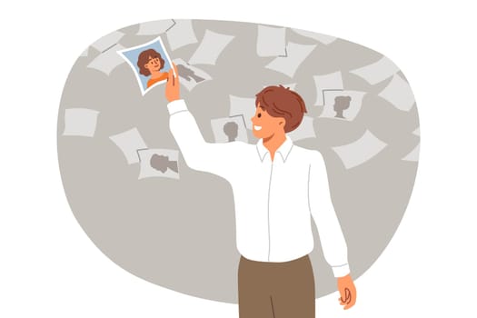 Man HR agent is recruiting personnel for corporation and selects photo of one employee from variety. Guy is busy building team for new startup and enthusiastically participates in recruiting staff