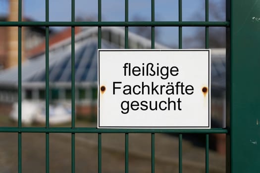 Sign with the German inscription fleissige Fachkräfte gesucht, as an indication of the shortage of trained specialists in Germany. Translation: hard-working skilled workers wanted
