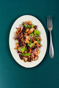 Autumn salad with stewed mushrooms, onions, lettuce and walnuts. Concept healthy food.