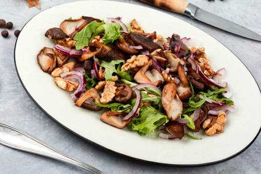 Autumn salad with stewed mushrooms, onions, lettuce and walnuts. Concept healthy food.