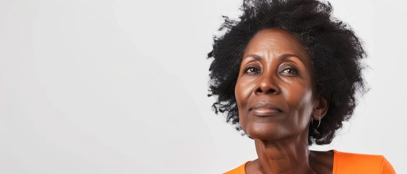 A portrait of a senior African woman gazing upwards, her expression a blend of wisdom and introspection. The subtle orange attire contrasts with her dignified grey hair