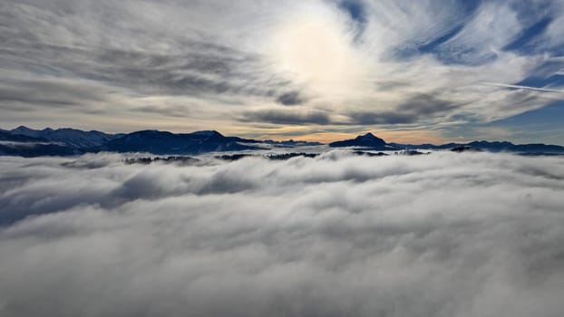 Drone shot in winter with fog in the valley and sun in the mountains