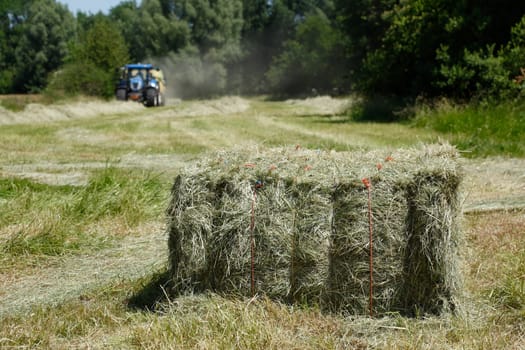 Straw bales on a cornfield with tractor during harvest, Lower Saxony, Germany
