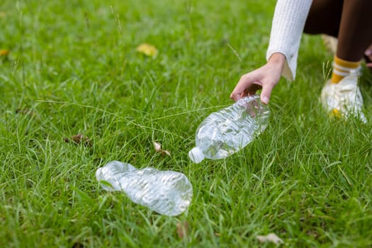 Woman hand collect plastic bottle from grass