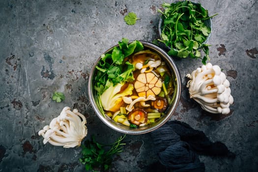 Beef and miso garlic broth, soup with vegetables, mushrooms and cilantro in a pot