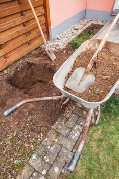 Wheelbarrow with soil and shovel, digging a hole for planting a tree or construction