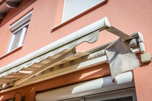 Old, messy, dirty and broken retractable awning installed on family house