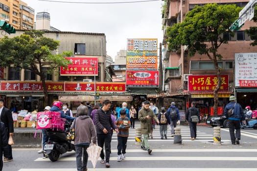 Taipei, Taiwan 05 February 2024: People cross the road in Donmen market district in Taipei city