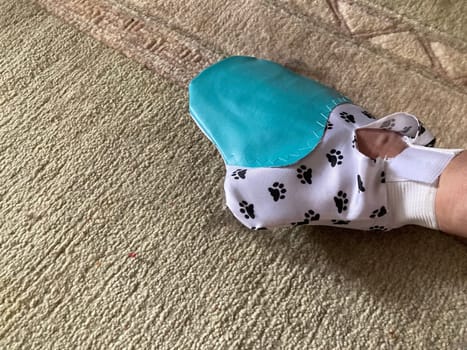 Using a glove to the remove cat hair from the carpet